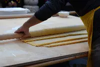 La maestria di una "sfoglina" nello stendere a mano un impasto in sfoglia sottile con l'ausilio del mattarello