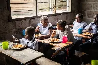 Allievi di una scuola di Kinshasa (Repubblica Democratica del Congo) usufruiscono del cibo fornito loro dal Programma Alimentare Mondiale (Wfp)